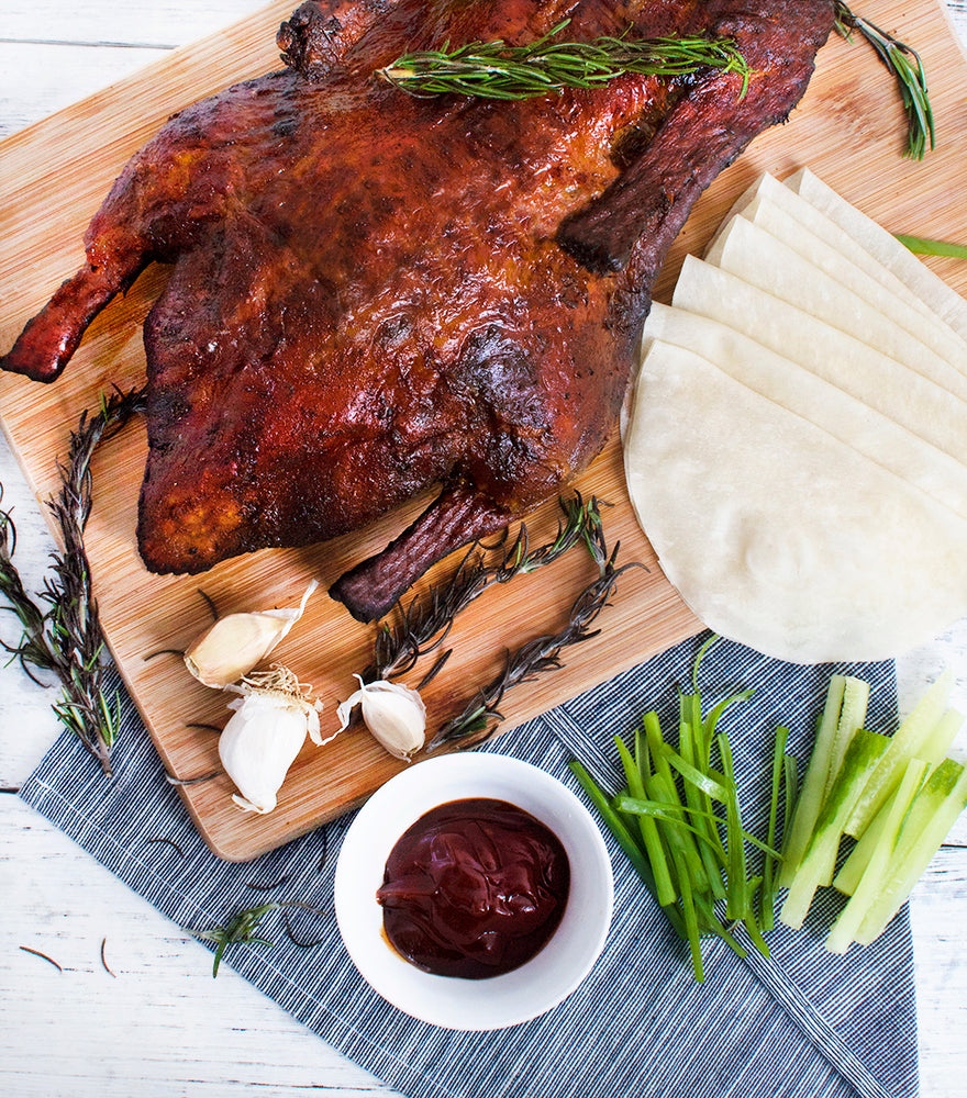 Delicious roasted Silver Hill Crispy Whole Duck with green onions, hoisin sauce and Chinese pancakes on a wooden board