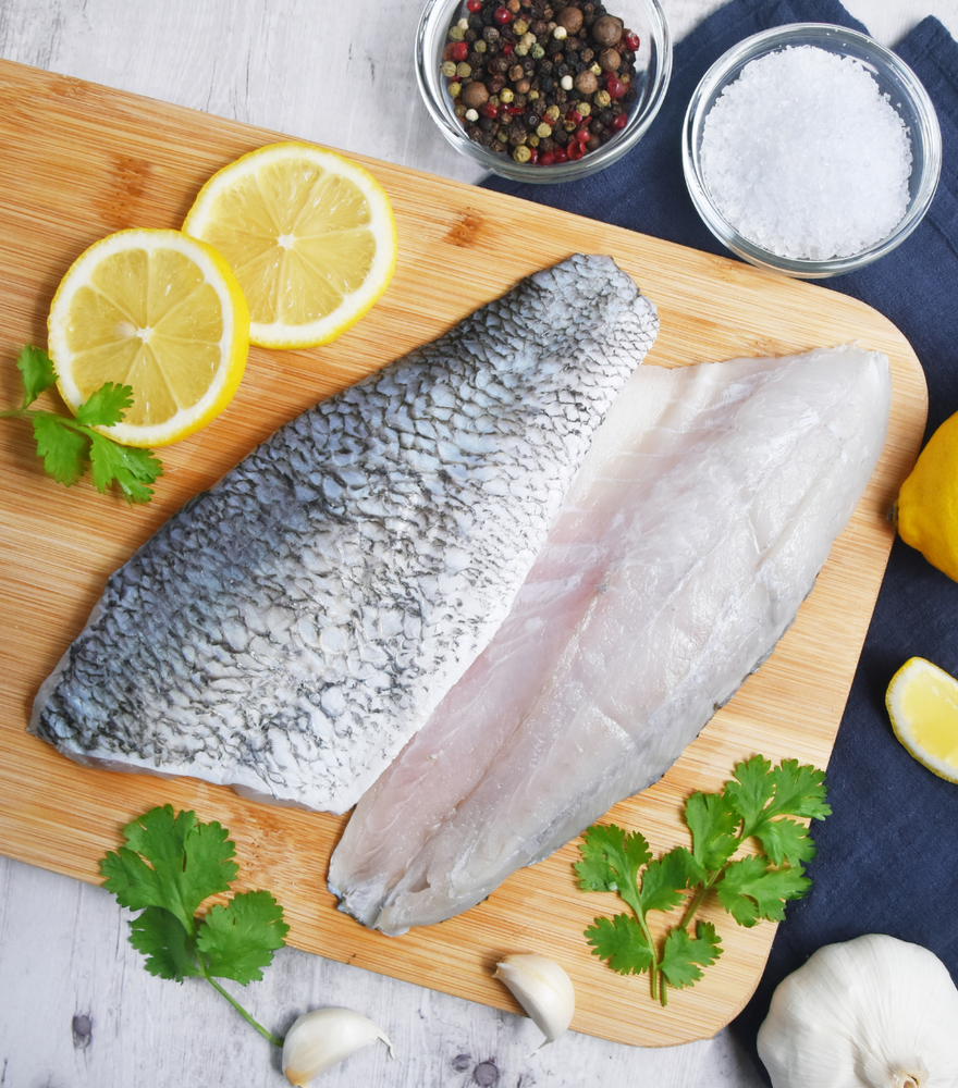 2 fresh Local Asian Seabass fillets with lemon sliced and black pepper aside