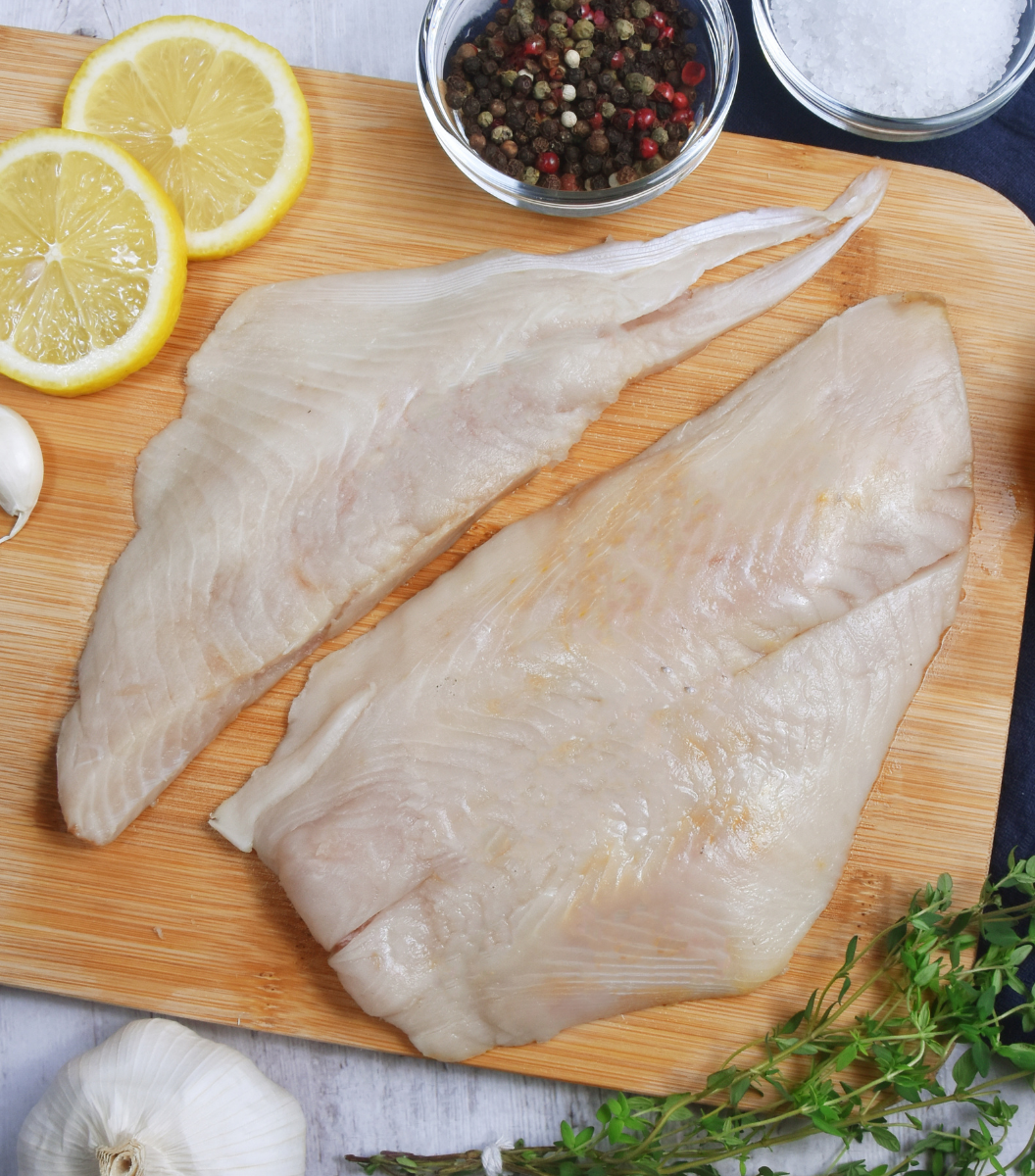 2 fresh New Zealand Ray Bream Fillet on a wooden board with lemon sliced, garlic and spices aside