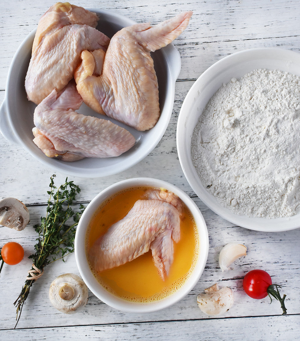 3 pcs organic chicken wings on a bowl and 1 chicken wing seasoned with egg